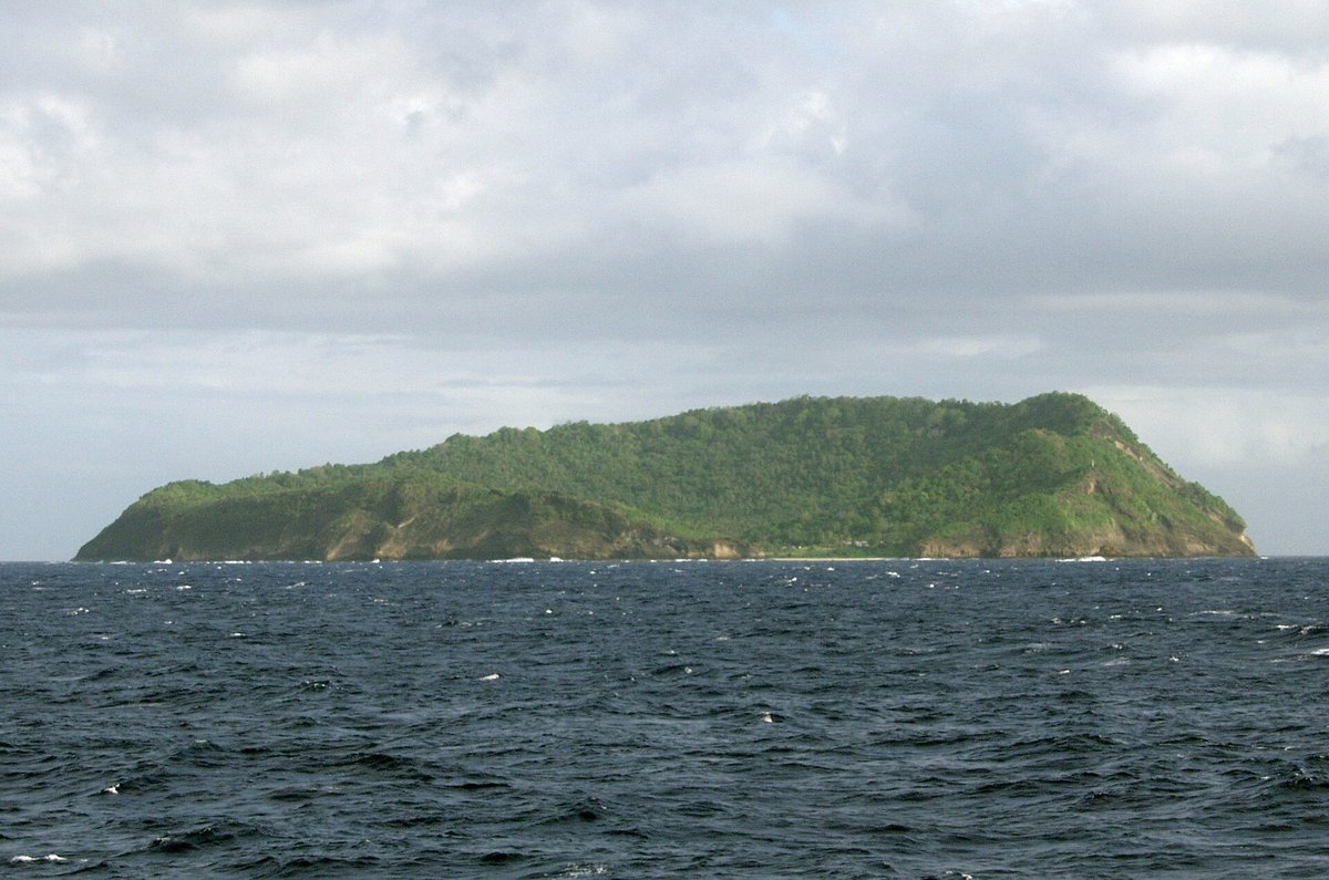 Apolima Island, a small green volcanic island rising from a dark blue sea, seen from the inter-island ferry