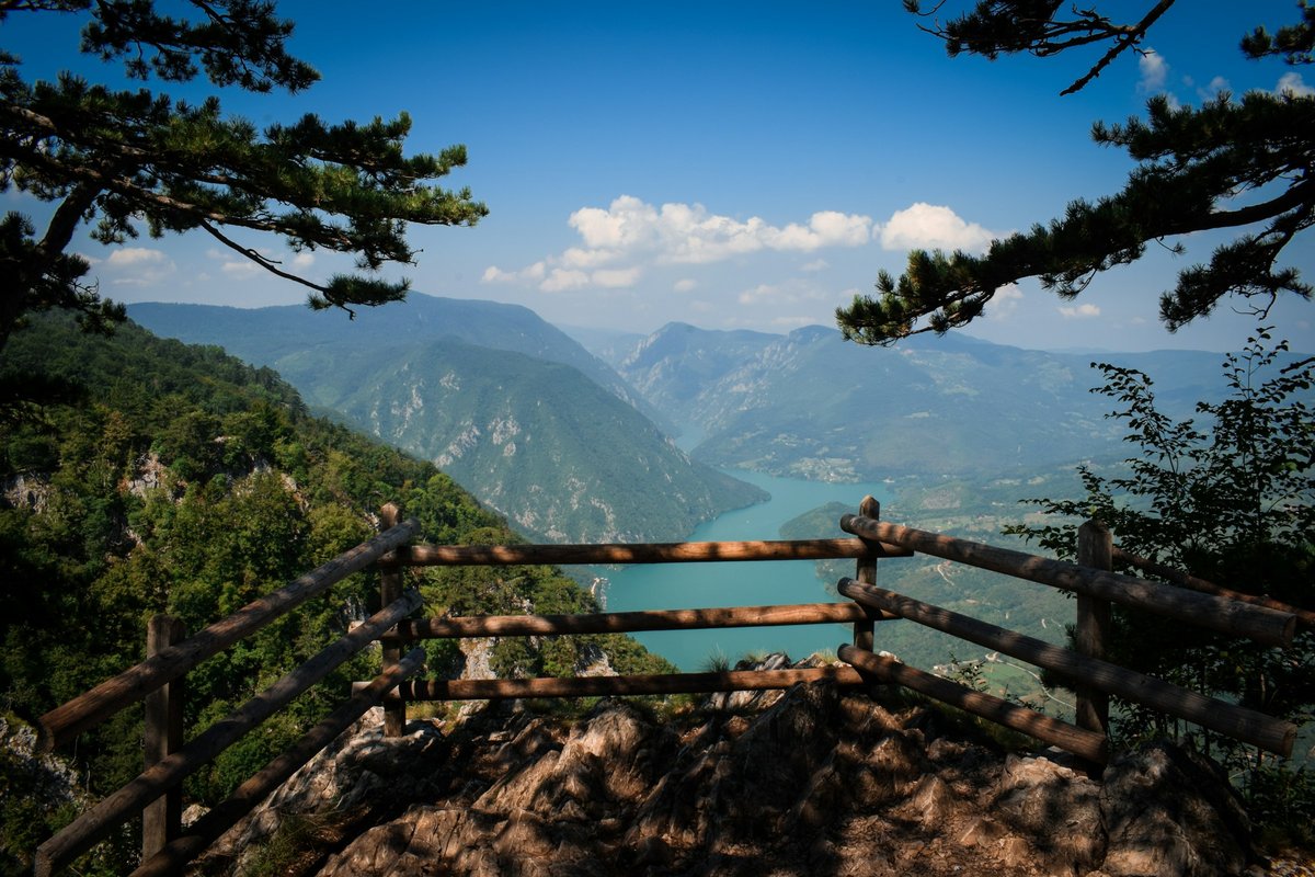 Wooden railing at Banjska Stena overlooking a reservoir and forested mountains in Tara National Park