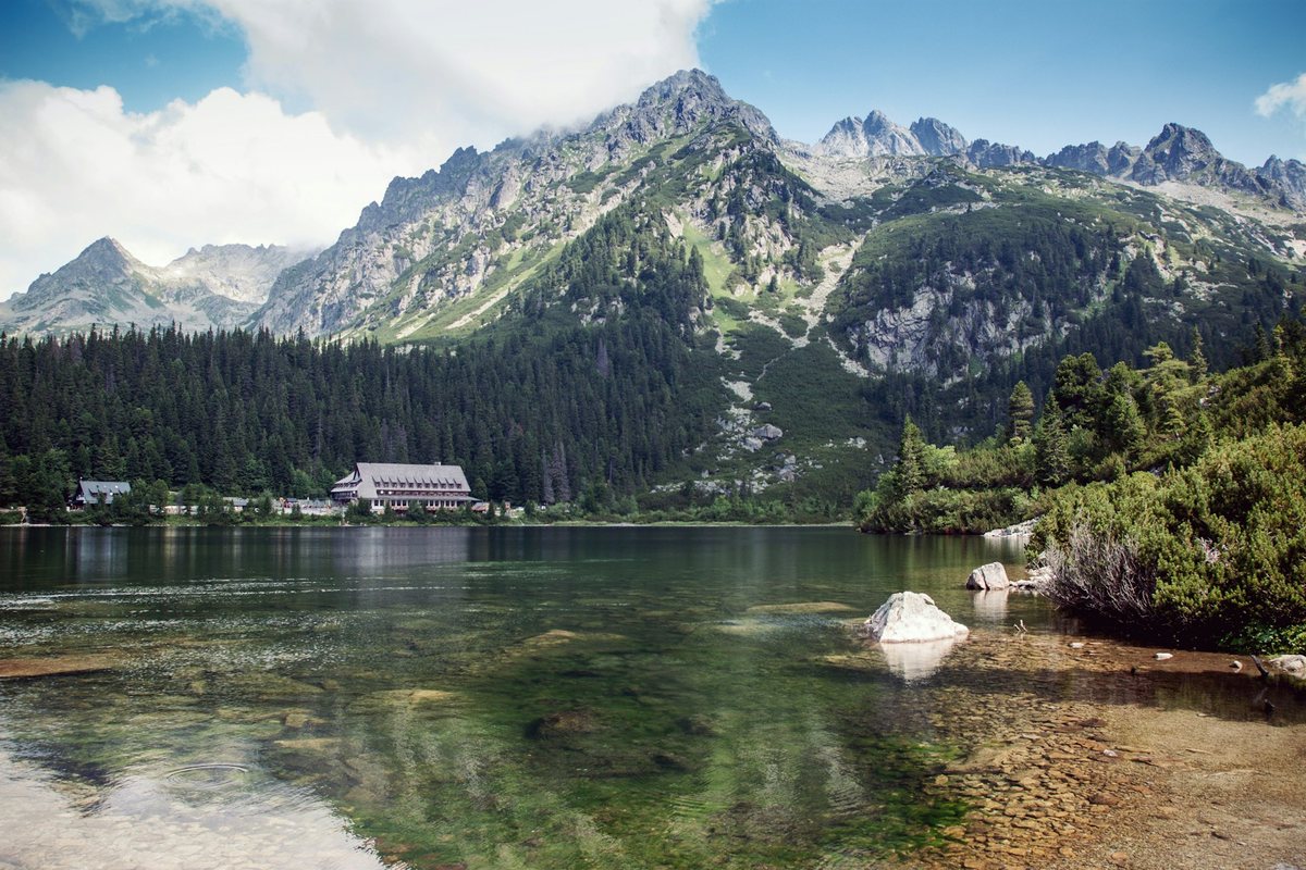 A mountain lake in the High Tatras with alpine forest and peaks beyond