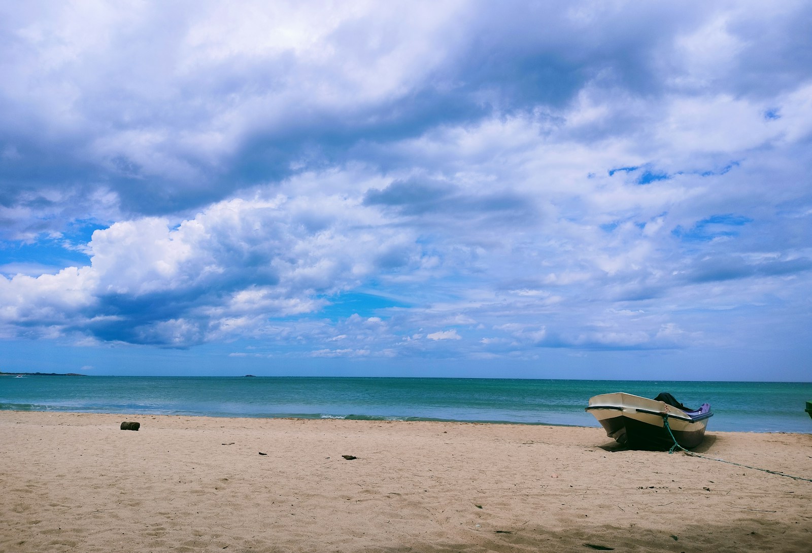 Boat resting on sandy Nilaveli beach with turquoise Indian Ocean water beyond