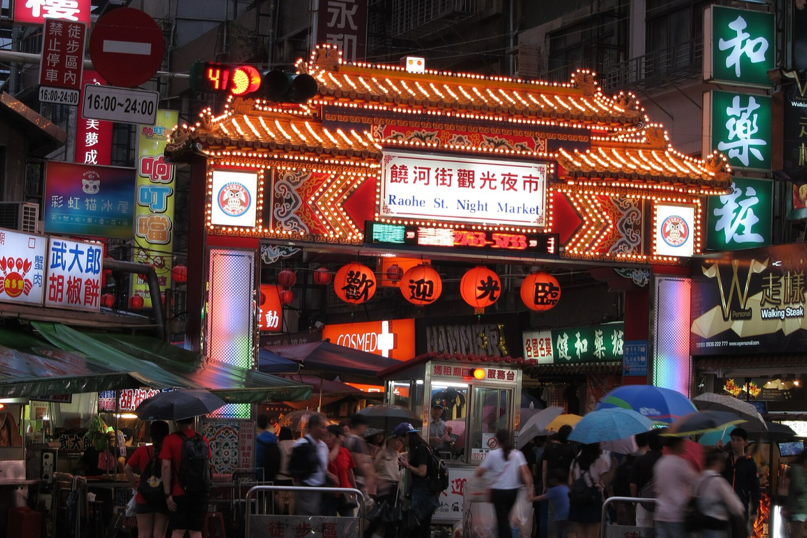 East entrance of Raohe Street Night Market in Taipei at night with neon lights and food stalls