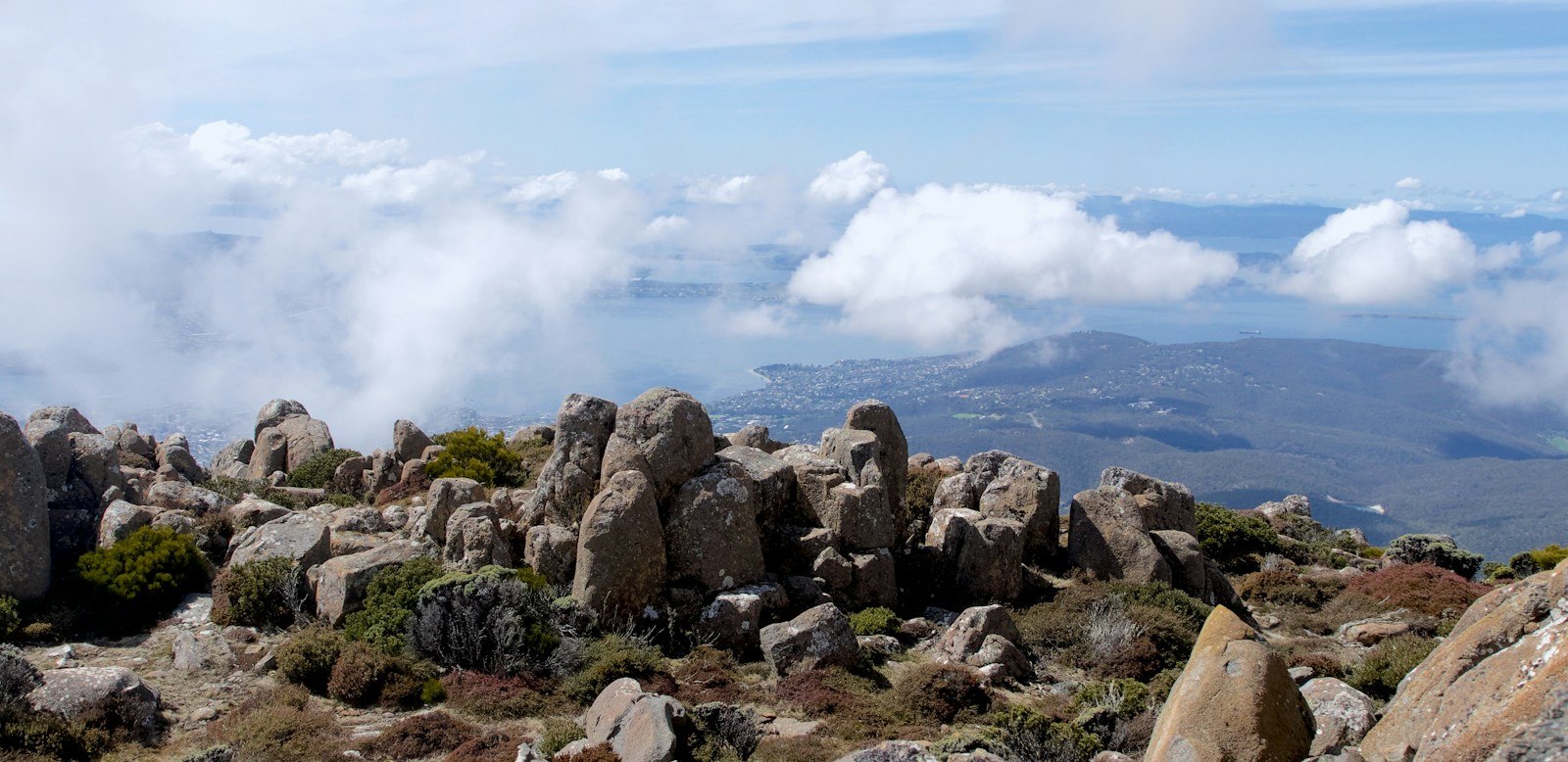 Mount Wellington with rocky alpine terrain, native vegetation and views across the surrounding landscape beneath drifting clouds