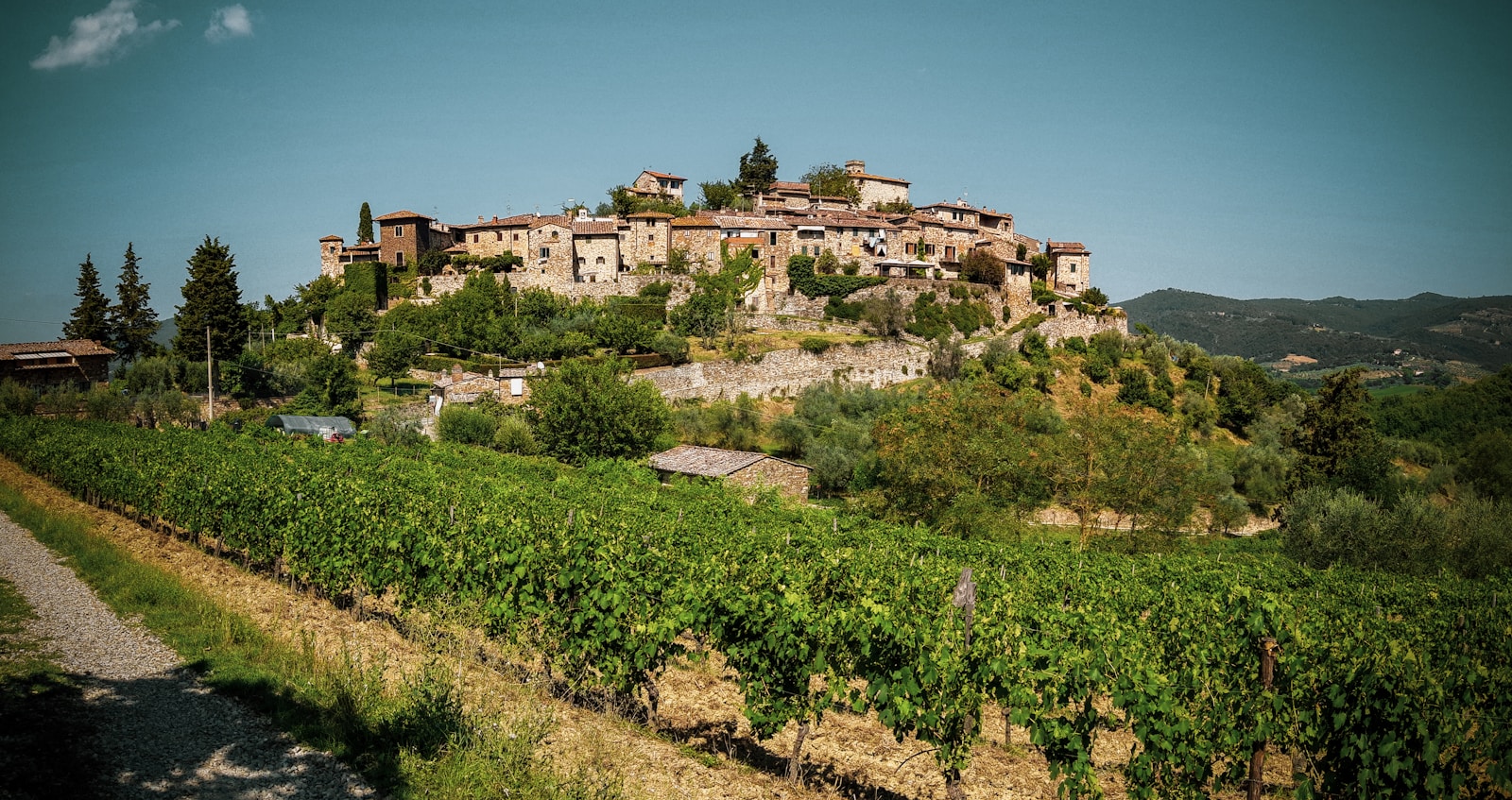 Hilltop Tuscan stone village above vineyard rows in the Chianti countryside