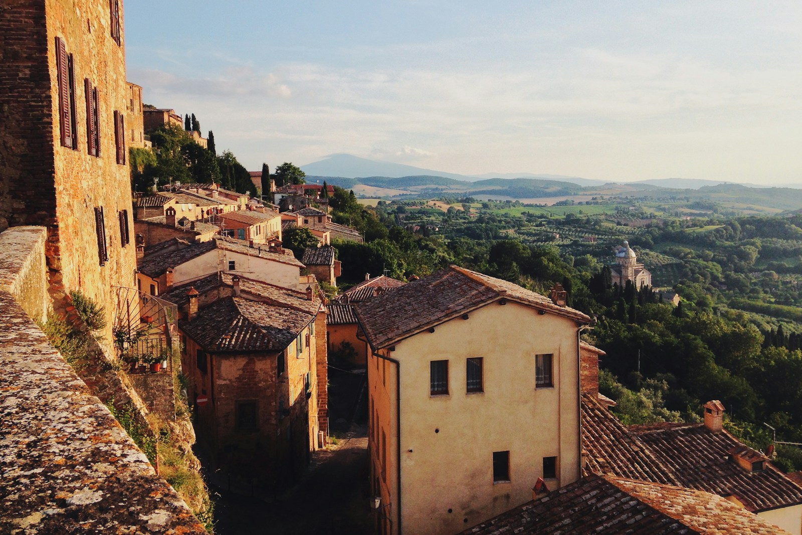 Hillside Tuscan town overlooking a broad valley at golden hour near Montalcino