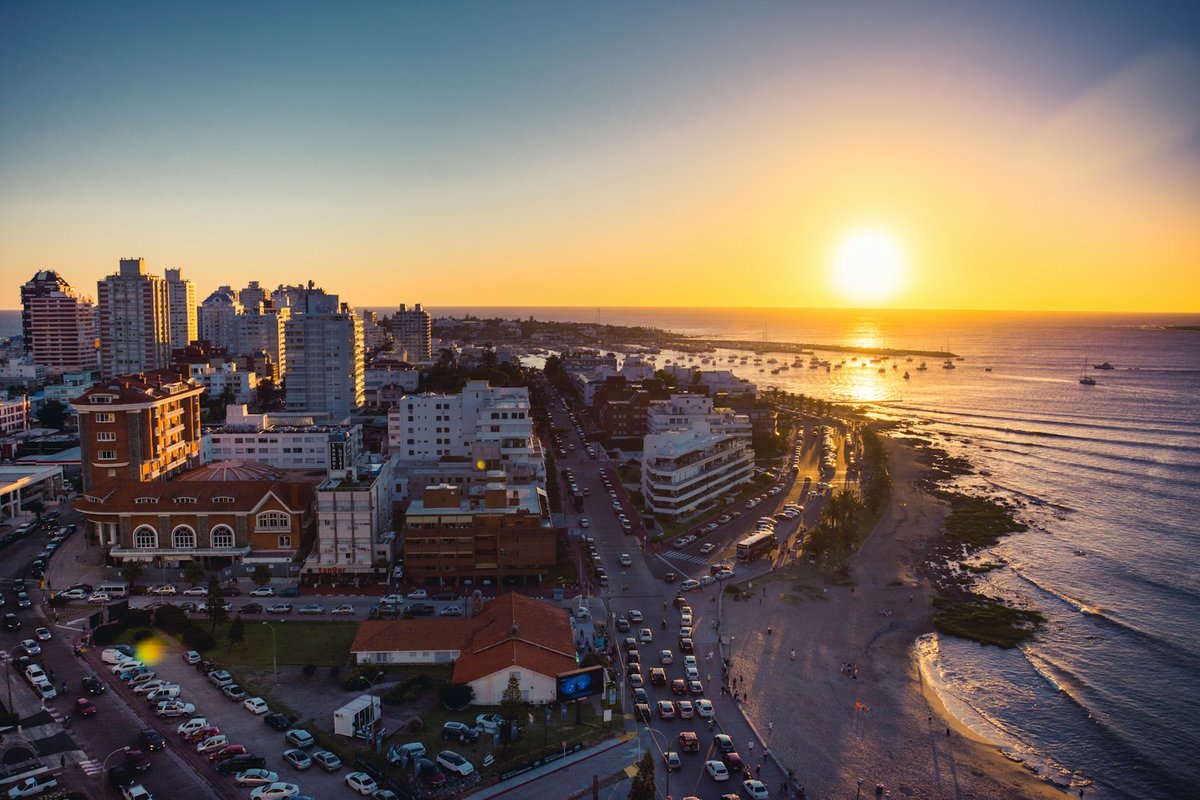 Vista aérea del atardecer sobre Punta del Este, con edificios altos, una playa curva y el océano Atlántico