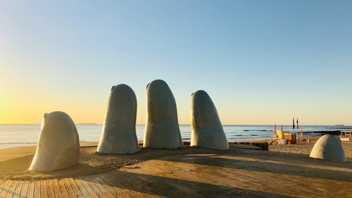 Los dedos blancos de la escultura La Mano surgiendo de una plataforma de madera sobre la playa de Punta del Este