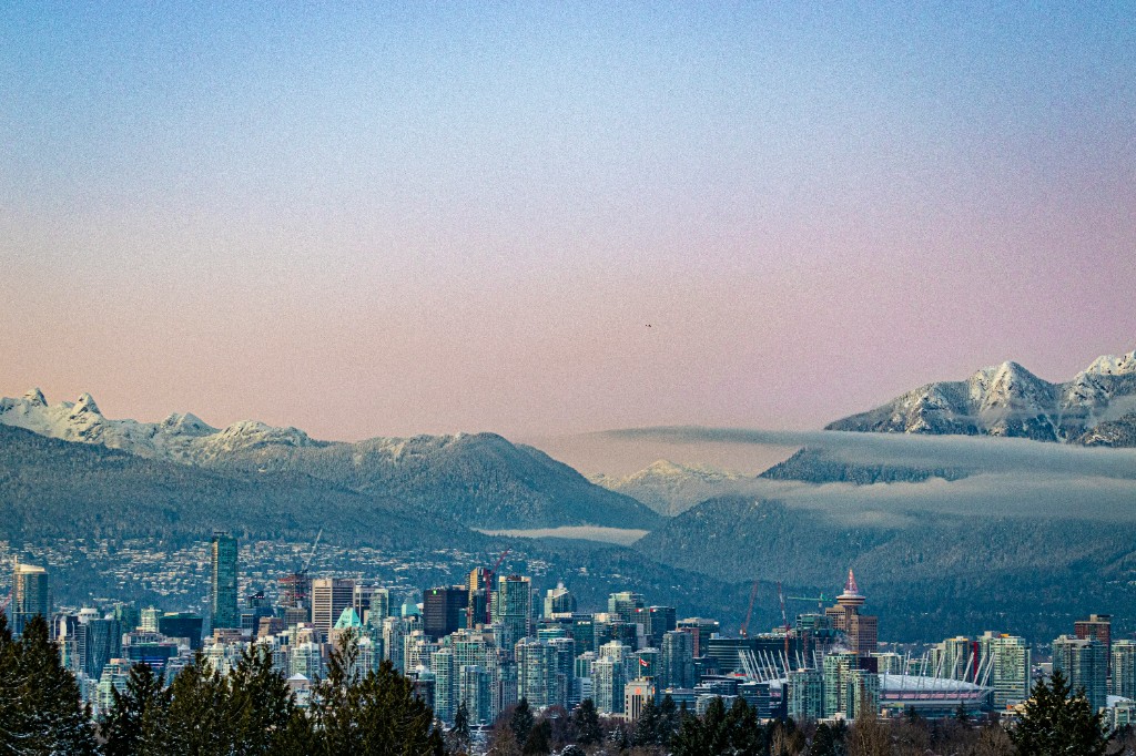 Vancouver downtown skyline with snow-covered mountains and a soft winter sunset sky