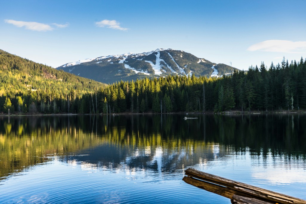 Mountain lake in Whistler reflecting evergreen forest and snow-dusted slopes